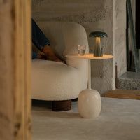 "Modern lamp with a green shade and white base, paired with a cozy cream sofa in a neutral-toned room."