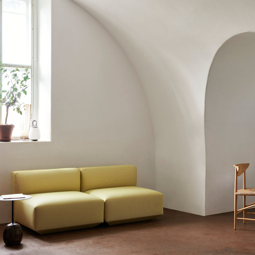 Yellow modular sofa with smooth, minimalist design, set against a neutral-toned room with earthy accents.