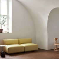 Yellow modular sofa with smooth, minimalist design, set against a neutral-toned room with earthy accents.