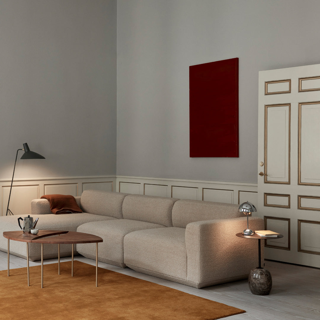 Neutral beige couch, rich terracotta rug, deep red wall art, and warm wooden accents in a modern living room setting.
