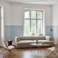 "Neutral beige sofa with minimalist chairs, soft blue and white walls, and warm wooden floor pattern."