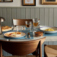 "Stylish dining table with blue plates, wooden accents, and warm earthy tones. Modern, inviting design elements."
