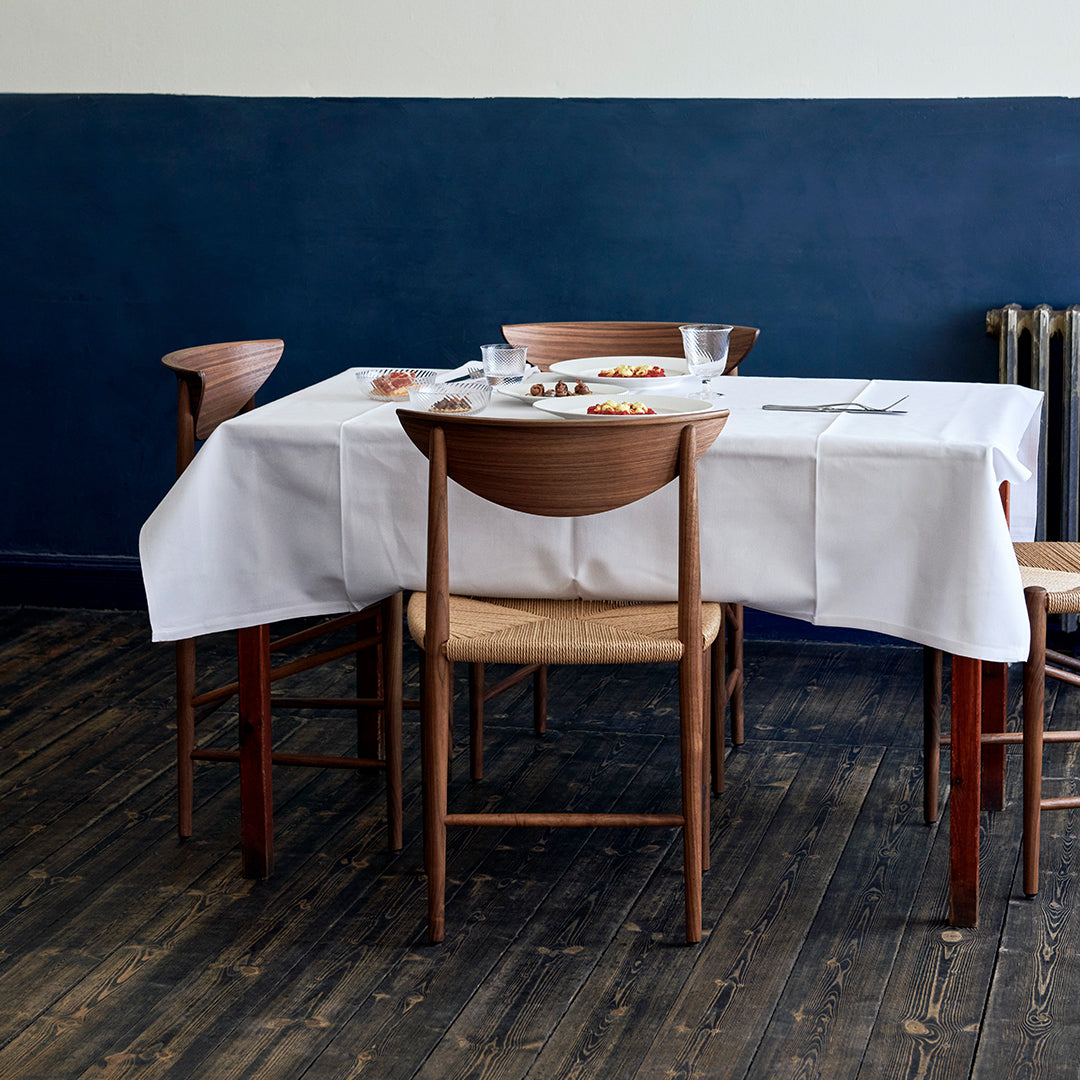 White tablecloth on wooden table, surrounded by natural wood and blue walls, creating a calm dining atmosphere.
