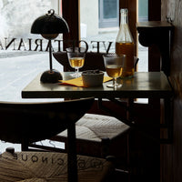 "Wooden table with neutral tones, patterned textile, and amber liquid in elegant glasses, creating a cozy atmosphere."