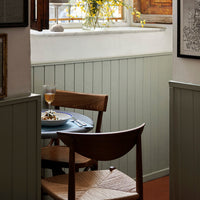 "Soft sage green walls, rustic wood chair, and blue tabletop create a cozy, inviting dining atmosphere."