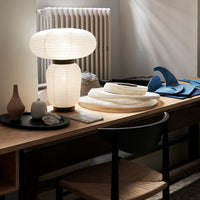 White paper lantern lamp on a wood table with blue and beige decor accents, featuring smooth textures and organic shapes.