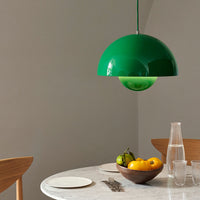 Glossy green half-dome pendant lamp with a seamless shine, complementing natural tones in a modern dining setting.