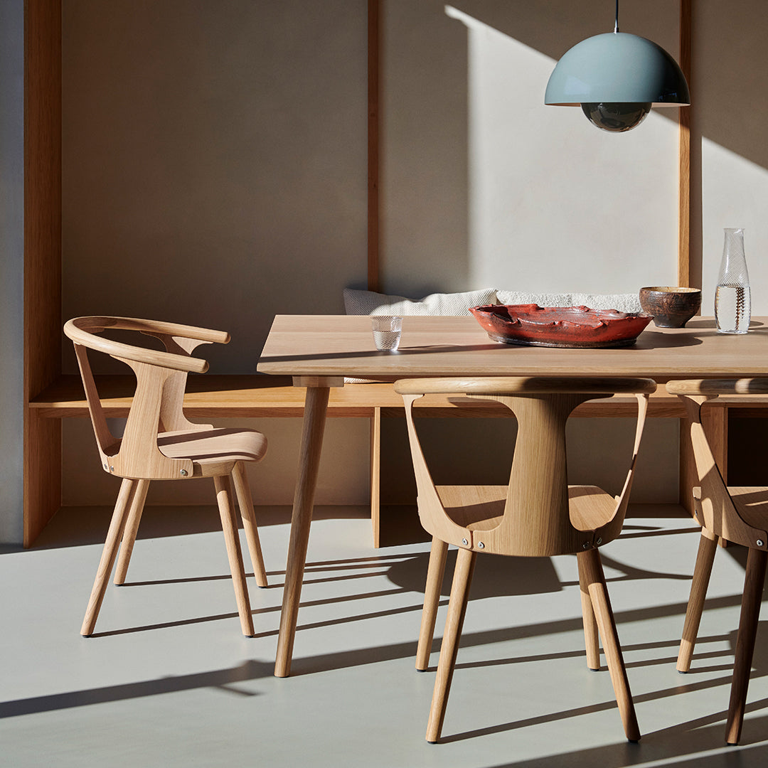 Light wood dining table with natural grain and minimalistic design, complemented by a soft blue pendant light.