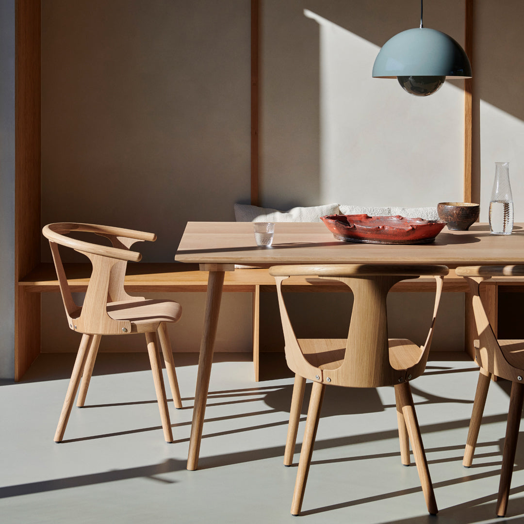 Natural wood table and chairs in a minimalist, light-filled space with earthy tones and soft blue accents.