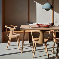 Natural wood table and chairs in a minimalist, light-filled space with earthy tones and soft blue accents.