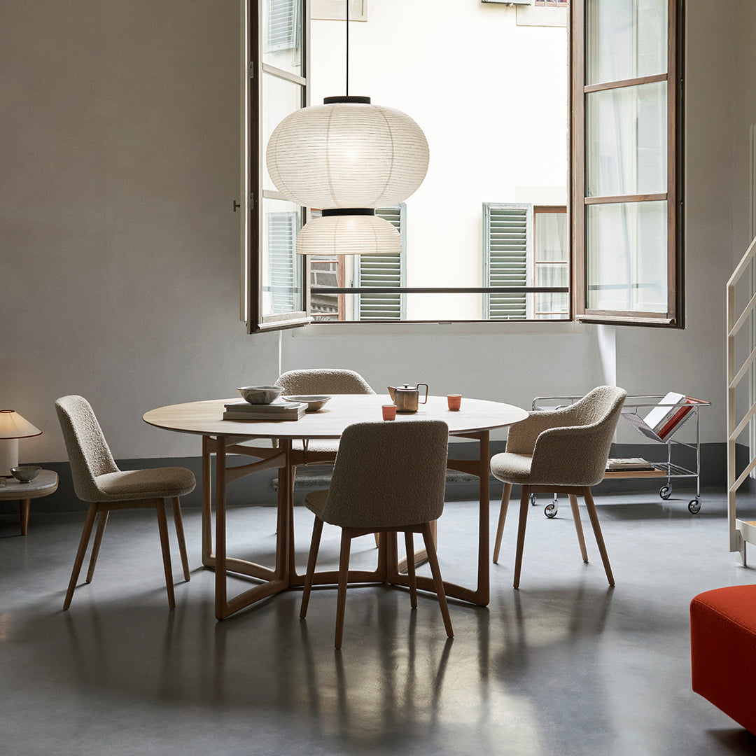 Modern wooden dining table with light gray chairs, accented by soft beige and white textures in a stylish interior.