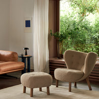 Beige textured armchair and ottoman in a bright, natural setting with wooden accents and soft lighting.