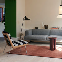 Black and white striped chair, grey couch, brown area rug, green accent wall, and modern decor elements.