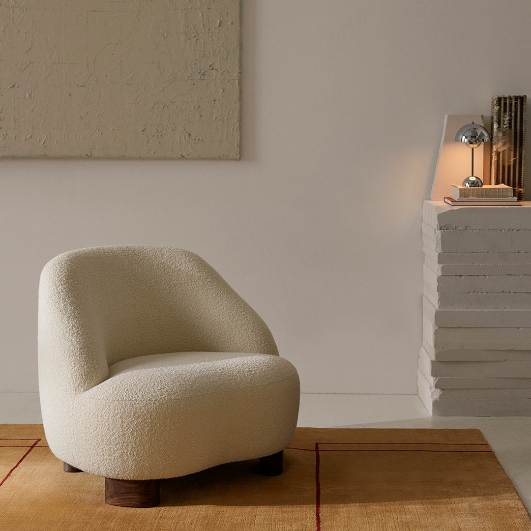 Cozy white boucle accent chair on a warm beige rug, featuring a simple, modern design and soft texture.