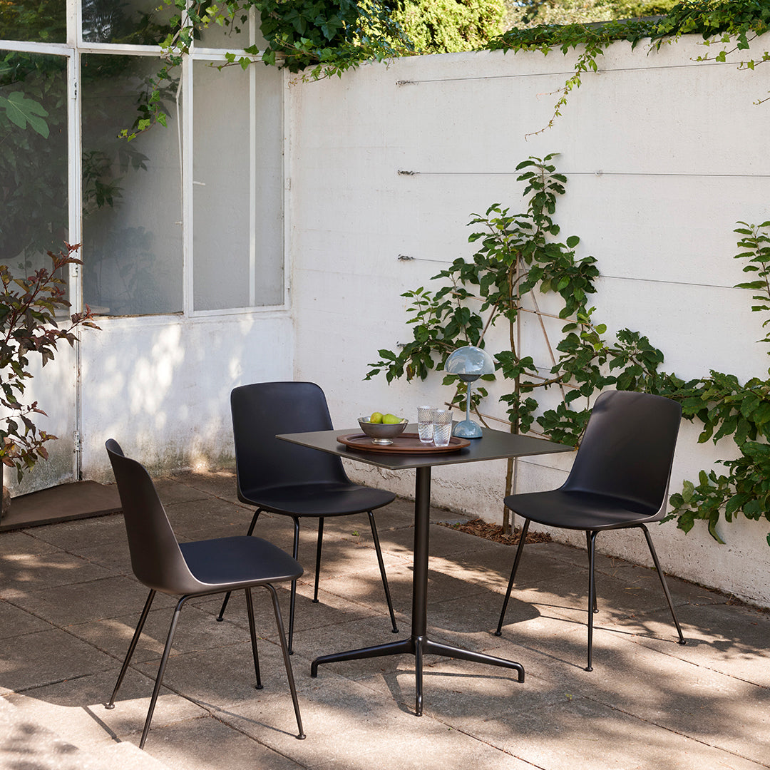 "Modern black dining chairs with sleek lines, paired with a minimalist round table in a natural outdoor setting."