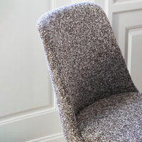 Gray textured chair with a soft, speckled pattern, complementing modern interiors.