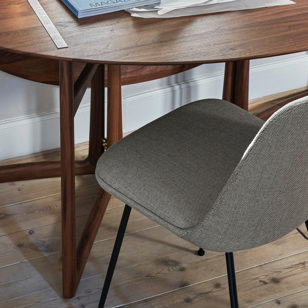 Gray fabric chair with a smooth finish, paired with a warm wooden table on a light wooden floor.