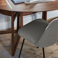 Gray fabric chair with a smooth finish, paired with a warm wooden table on a light wooden floor.
