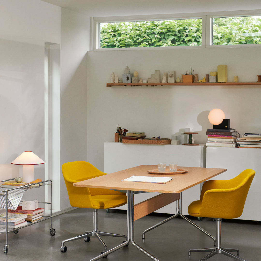 Bright yellow chairs and a light wood table in a modern workspace with neutral walls and a minimalist decor.