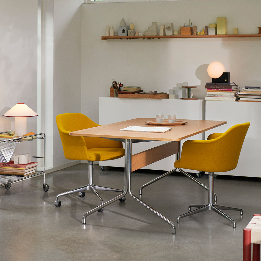 Modern office setup featuring a light wood table and two bright yellow chairs against a neutral backdrop.