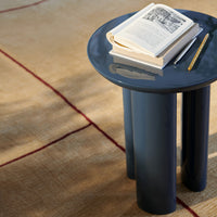 Round navy blue side table with a glossy finish, complemented by a beige patterned rug.