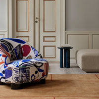 Colorful patterned chair featuring bold blue, red, and black designs on a light background, set in a modern interior.