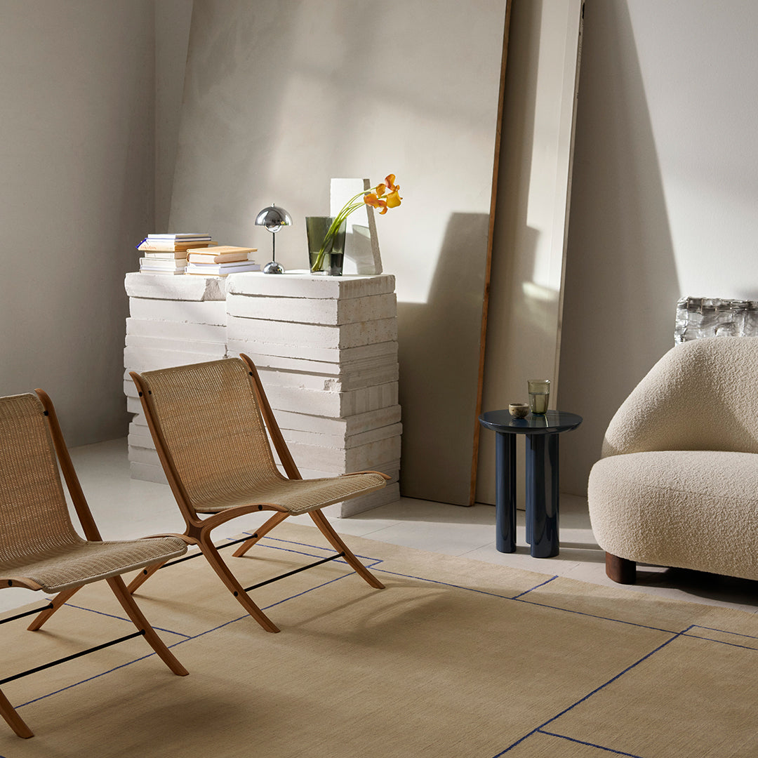 "Neutral-toned living room with pale beige, warm wood accents, and soft textures, featuring a simple pattern on the rug."