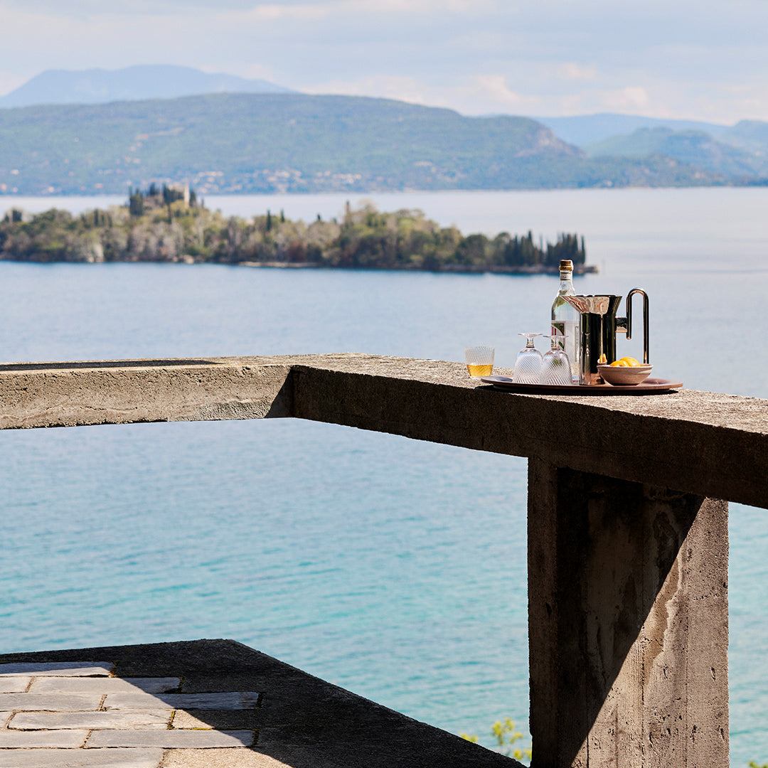 "Coastal view with muted blues and greens, accented by earthy tones of stone and natural textures on a rustic table."