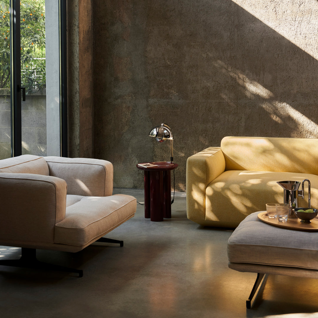 Modern living room featuring a light beige armchair and a vibrant yellow sofa, with a sleek wooden side table.