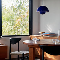 Modern dining room featuring a deep blue pendant light, natural wood tones, and a woven chair detail.