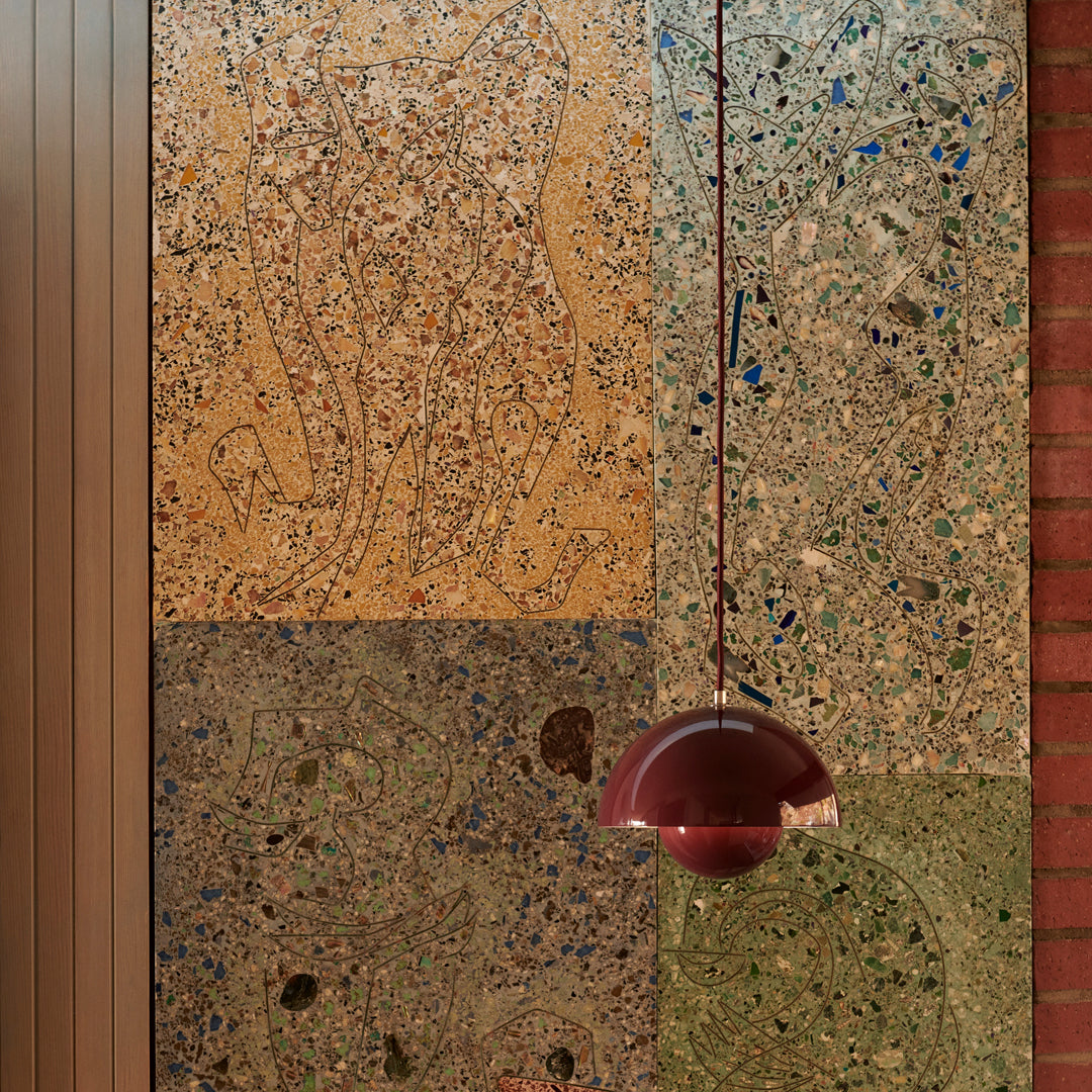 Textured wall panels in shades of amber, green, and earthy tones with intricate patterns and a burgundy pendant light.