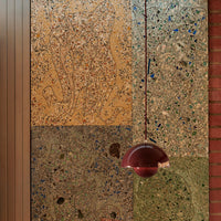 Textured wall panels in shades of amber, green, and earthy tones with intricate patterns and a burgundy pendant light.
