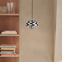 Black and white patterned pendant lamp, showcasing wavy designs, against a neutral wall and wooden shelving.