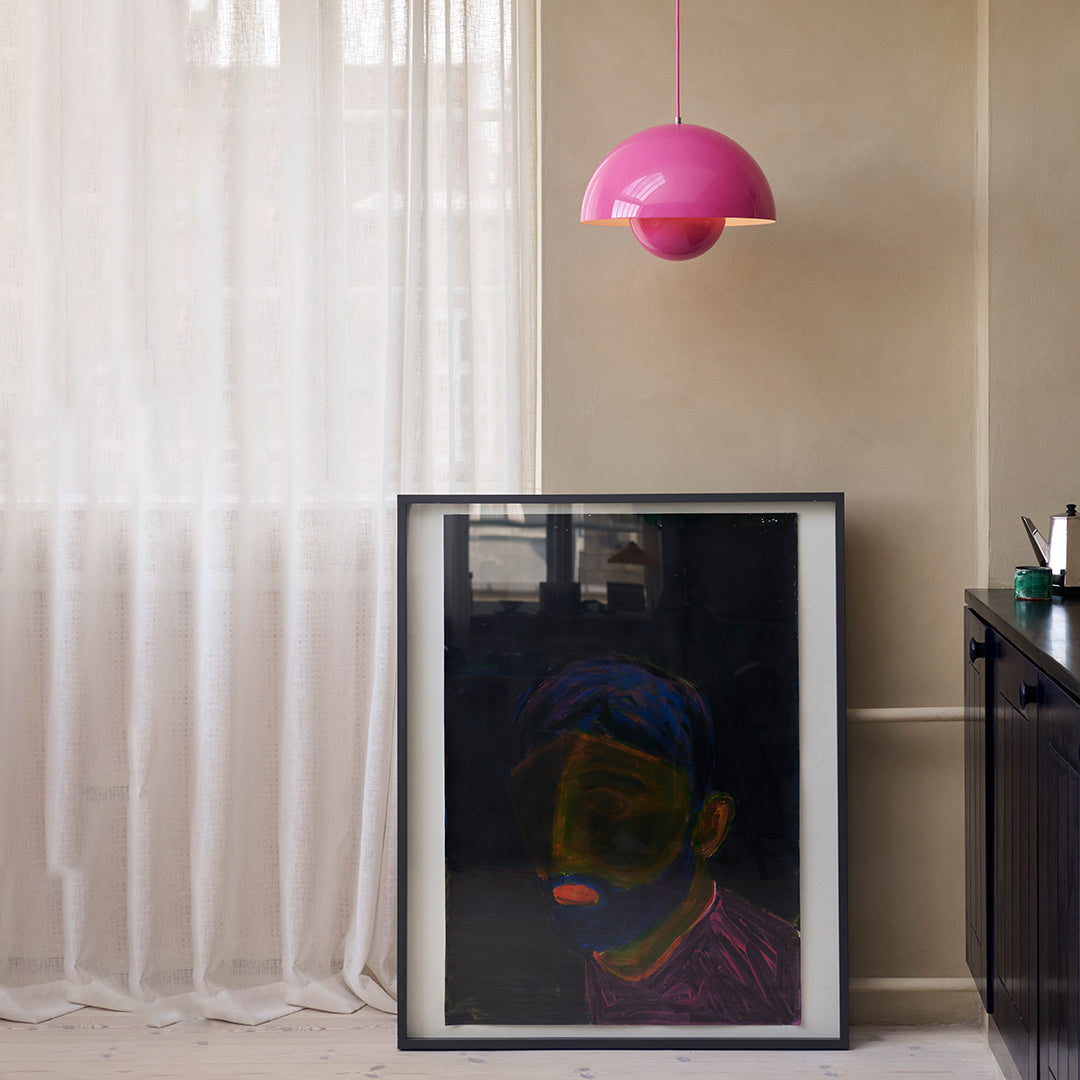 Framed artwork featuring vibrant colors with neon highlights, complemented by a bold pink pendant lamp.