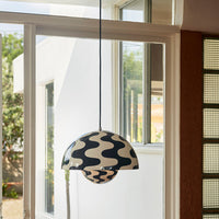 Black and white wavy patterned pendant lamp hanging in a bright, airy space, showcasing modern design.
