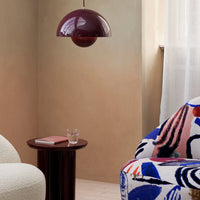 Colorful patterned chair featuring bold blues, reds, and abstract shapes, with a sleek burgundy pendant lamp above.