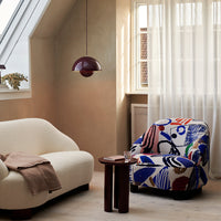 Colorful patterned armchair with abstract designs in blue, red, and black, complemented by a neutral sofa.