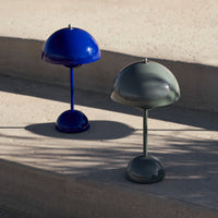Two modern table lamps in deep blue and muted olive green with sleek dome shapes and circular bases.
