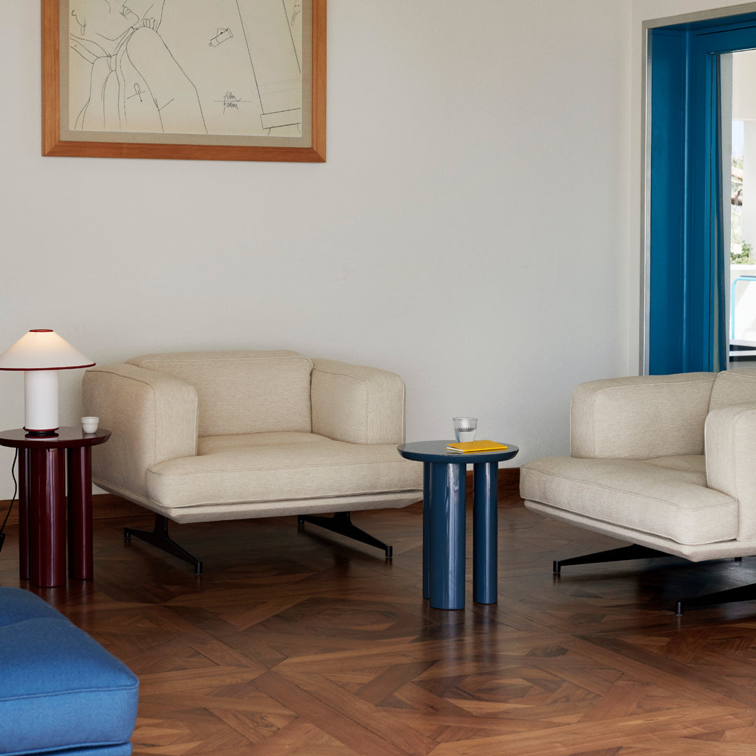 Beige sofas, dark wooden coffee tables in red and blue, and a blue accent wall, creating a modern interior aesthetic.