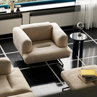 Beige upholstered armchair on black and white tiled floor. Modern design with clean lines and minimalist elegance.