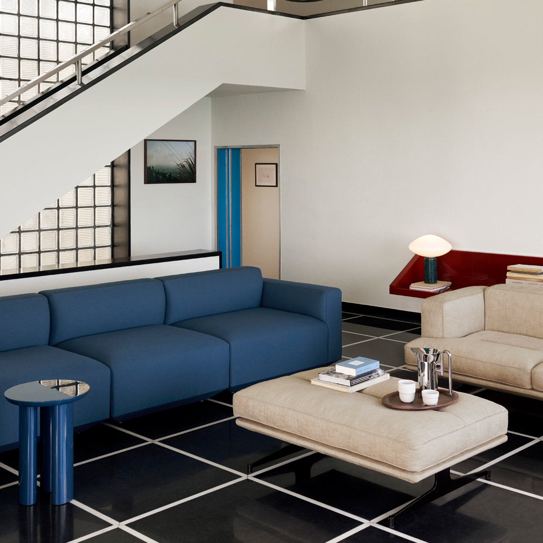 Modern living room featuring a navy blue sofa, beige armchair, and patterned black and white flooring. Stylish and contemporary decor.