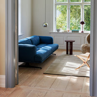 Modern living room featuring a deep blue sofa, light wood floors, and a neutral area rug with soft textures.