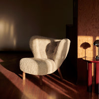 Cozy cream chair with soft, textured upholstery and wooden legs, casting warm shadows in a stylish interior setting.
