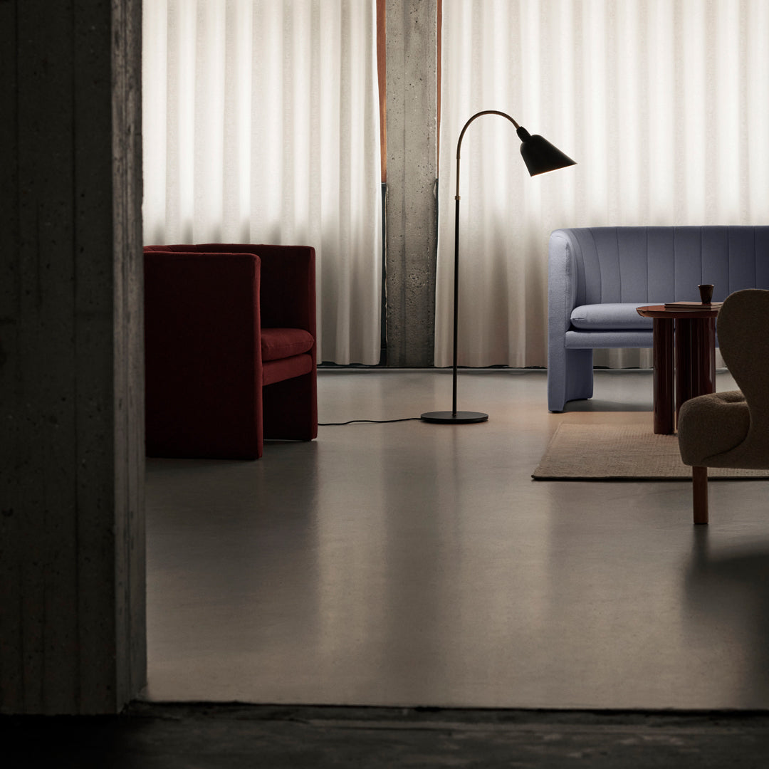 "Modern living room with red and blue sofas, neutral walls, and soft light filtering through sheer curtains."