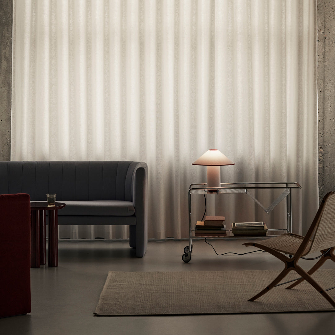 "Elegant beige textured curtains with subtle vertical stripes; modern gray sofa, wooden side table, and neutral accents."