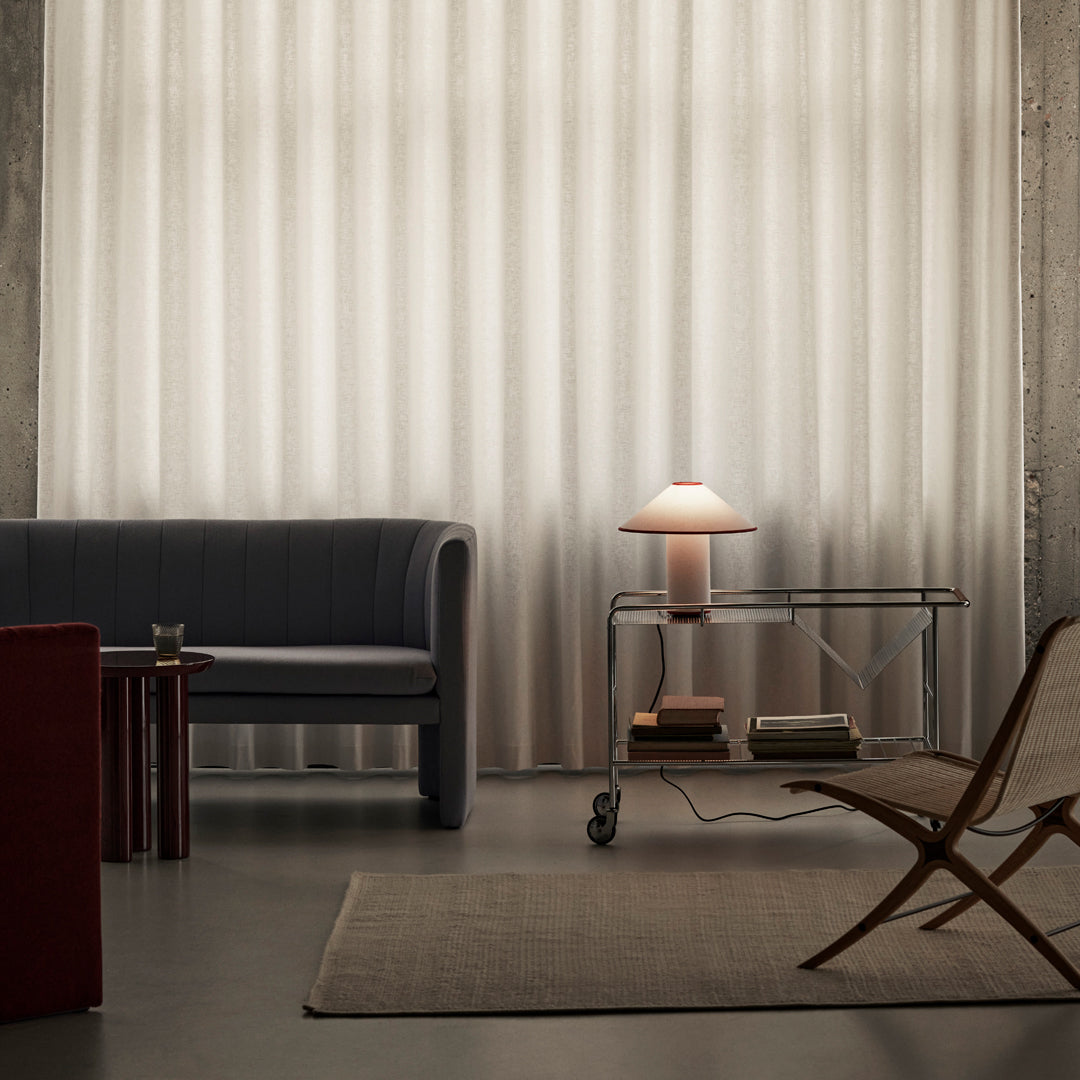 Neutral tones with a textured, sheer curtain, a gray sofa, and warm wood accents in a modern living room setting.