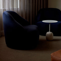 Navy blue curved chairs with a sleek white table against warm beige carpet and soft natural light.