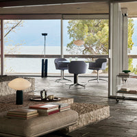 Modern living room featuring gray furniture, earthy tones, and textured patterns, framed by large windows.