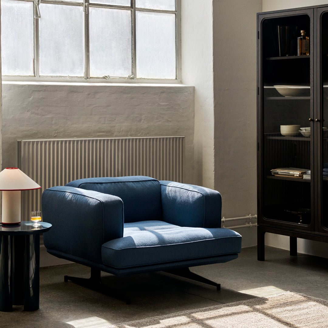 Blue contemporary armchair with a sleek design, set against a neutral-toned interior.