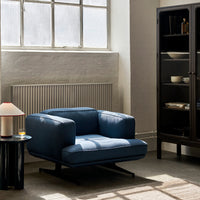 Blue contemporary armchair with a sleek design, set against a neutral-toned interior.